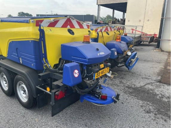 Op de afbeelding ziet u de achterkant van enkele geelblauwe strooiwagens staan