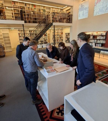 Het college staat gebogen over een kast en bestudeerd stukken van het ECAL