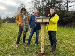 Wethouder Hans van der Noordt (midden) bij de plaatsing van een bijenhotel, een klein houten huisje op een houtenpaal