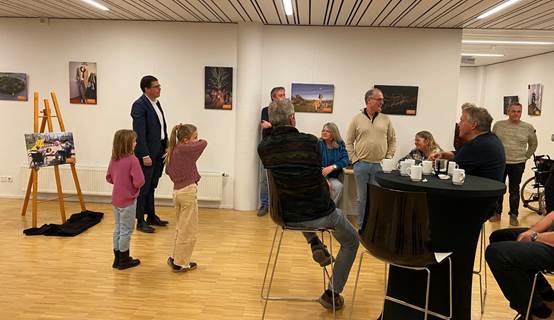 Burgemeester Joost van Oostrum opende samen met de betrokkenen van de projecten de expositie. Hij staat bij een schildersezel met daarop een afdruk van een foto