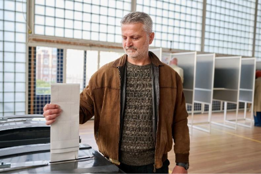 Foto ter illustratie. Man steekt zijn stembiljet in een stemcontainer